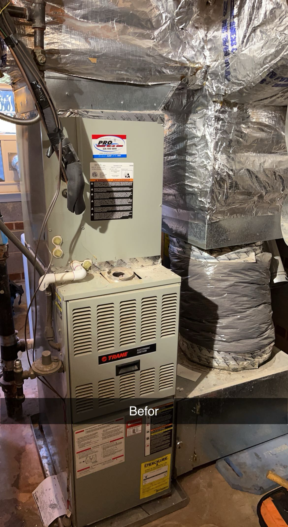 A beige Trane furnace unit in a basement with exposed ductwork and insulation; dust is visible on top. The word Before appears at the bottom of the image.
