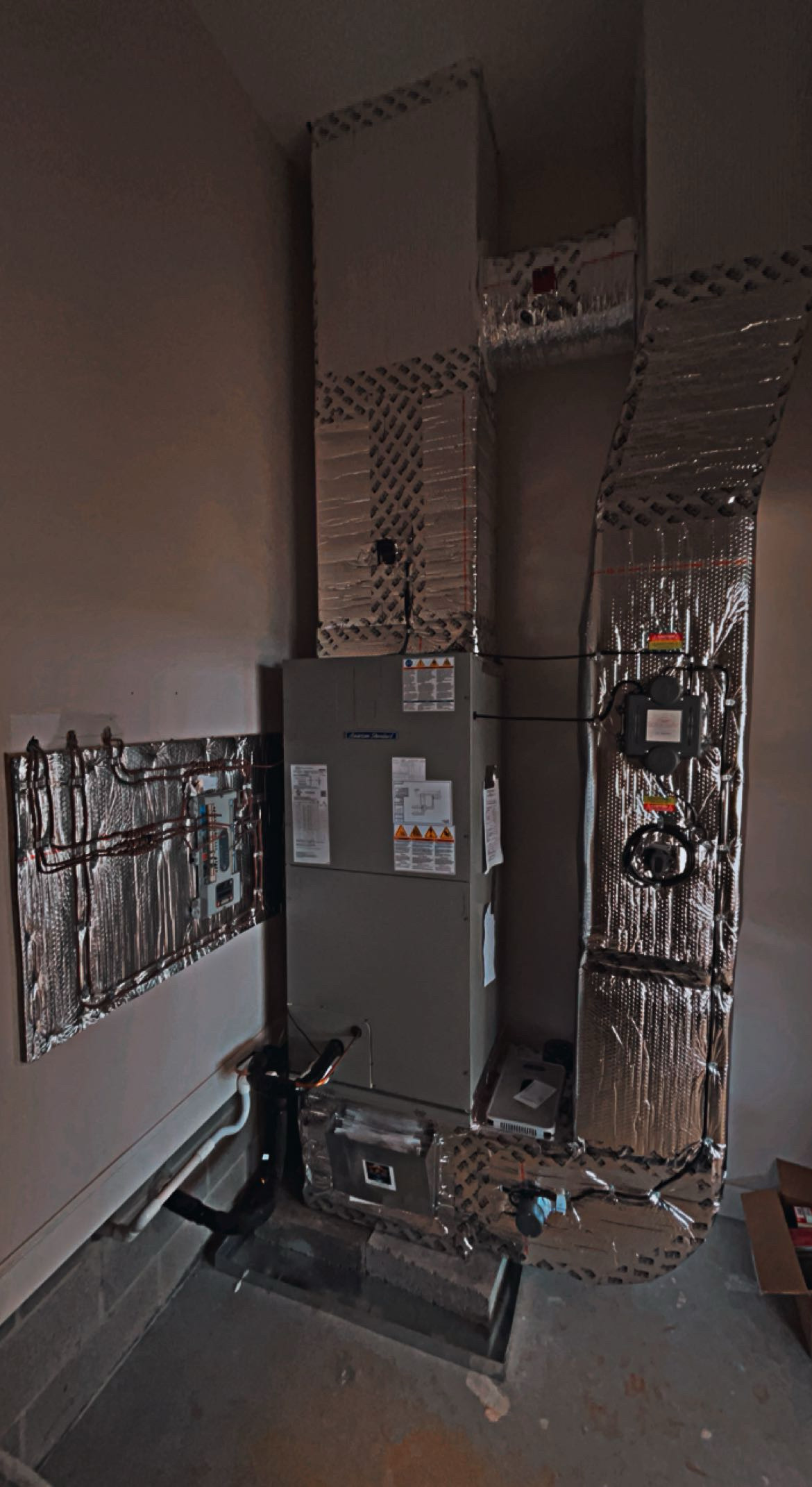 Heating, ventilation, and air conditioning (HVAC) unit with insulated ducts and control panels installed in a utility room.